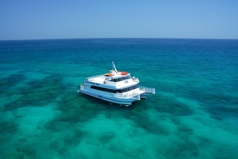 A glass Bottom-boat sails out to the coral reef among the pristine waters.