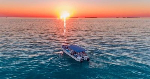 Power catamaran causing the blue waters ion Key West with the sunset in the background
