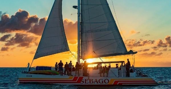 A small sail Catamaran and it's passengers cruise by the lovely Key West sunset.