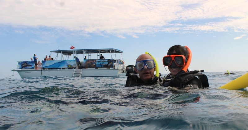 2 people in all the snorkel equipment enjoying seeing whats beneath the waters.
