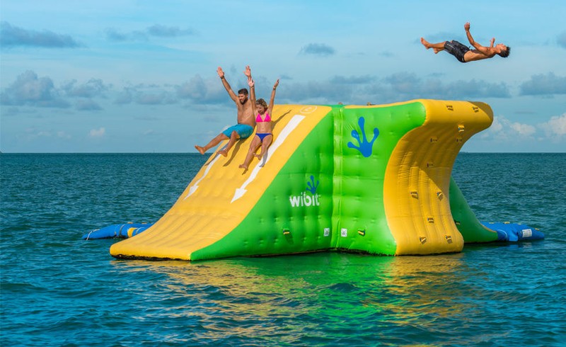 People slide down the waterslide, bounce around and jump in the water on the ultimate adventure.