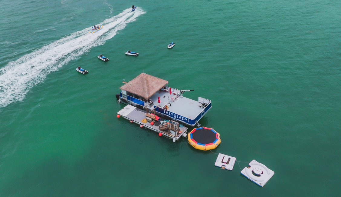 picture of tiki hut floating on the ocean with jet skis and kayaks all around